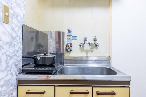 a kitchen with a sink and a pot on a stove at エステラス大阪ウエスト103 in Osaka