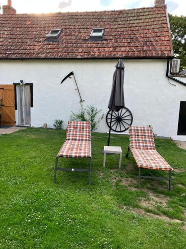 two chairs and an umbrella in a yard at Petite maison dans la nature in Préveranges