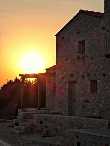 an old stone building with the sunset in the background at Terra Di Pietra Exclusive Suites & Apartments in Areopolis