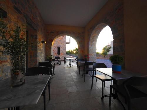 an empty restaurant with tables and chairs and windows at Terra Di Pietra Exclusive Suites & Apartments in Areopolis