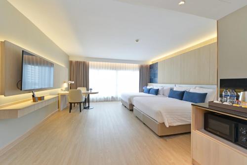 a hotel room with a bed and a desk and a tv at Centre Point Plus Hotel Pratunam in Bangkok
