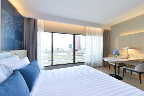 a hotel room with a large bed and a desk at Centre Point Plus Hotel Pratunam in Bangkok