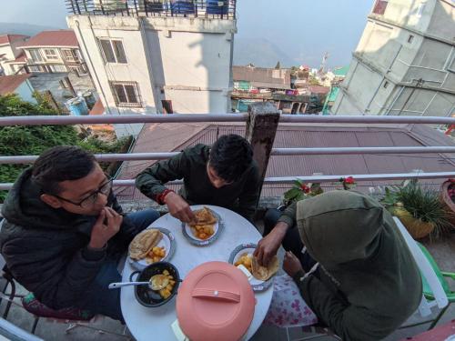 a group of people sitting at a table eating food at International Youth Hostel and Homestay Kurseong Bazar in Kurseong