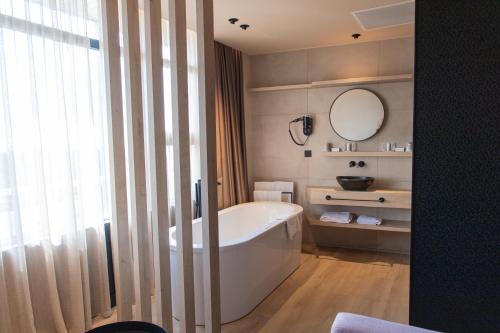 a bathroom with a white tub and a mirror at Palace Hotel Zandvoort in Zandvoort