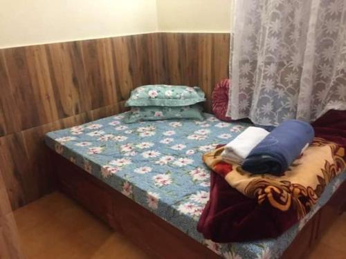 a small bed with a quilt and pillows on it at International Youth Hostel and Homestay Kurseong Bazar in Kurseong