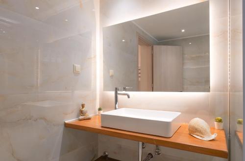 ein Badezimmer mit einem weißen Waschbecken und einem Spiegel in der Unterkunft Mirabilia deluxe apartment in Arillas