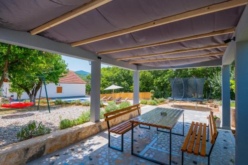 a patio with a table and chairs and a swing at Holiday House Tone, Imotski-Drum-Makarska in Drum