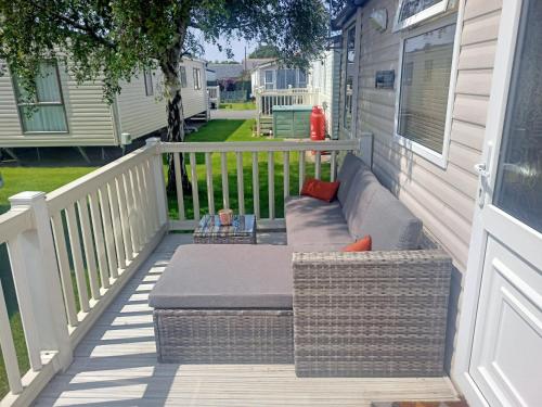 a porch with a couch on the side of a house at 2 Bedroom Static Caravan C3 on quiet park near Talacre and Prestatyn in Prestatyn