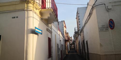 Casa Vacanze Arturo في باري: زقاق ضيق وبه مباني بيضاء ولوحة زرقاء