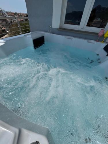 a bath tub filled with blue water with a window at Vista Mare Apartments in Giardini Naxos