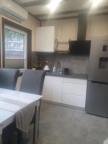 eine Küche mit weißen Schränken, einem Tisch und einem Kühlschrank in der Unterkunft POKÓJ RODZINNY SERCE KRYNICY in Krynica Morska