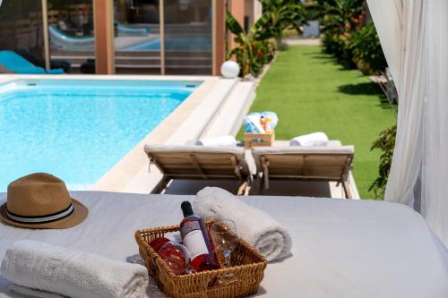 Modular Bungalows With Heated Pool Artemis Greece في أرتيميدا: سلة من النبيذ وقبعة على طاولة بجوار حمام السباحة