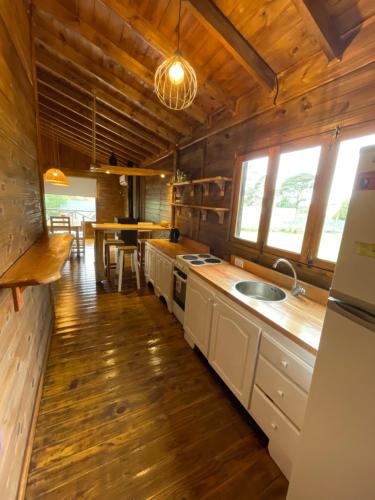 a kitchen with white cabinets and a wooden floor at Cabaña Los acantilados in Mar del Plata
