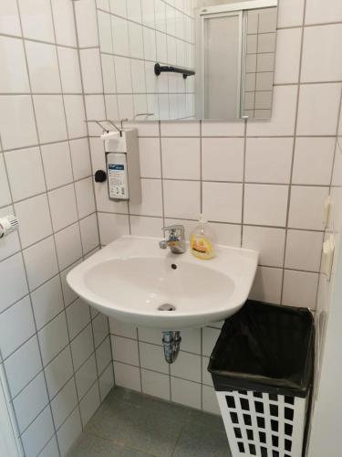 a white bathroom with a sink and a mirror at 2 Bett Zimmer in Ramstein-Miesenbach
