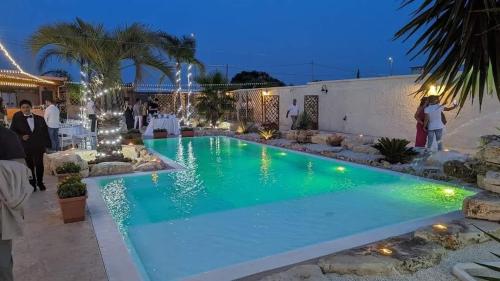 a pool at night with people standing around it at Il Germoglio in Bisceglie