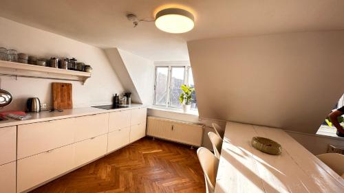 コペンハーゲンにあるCarolinas Apartment - Studie 4th floorの白いキャビネットとテーブル、窓付きのキッチン