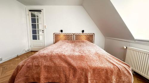 Un dormitorio con una cama con una manta naranja. en Carolinas Apartment - Studie 4th floor, en Copenhague