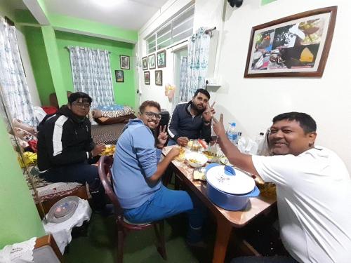 a group of men sitting around a table eating food at International Youth Hostel and Homestay Kurseong Bazar in Kurseong
