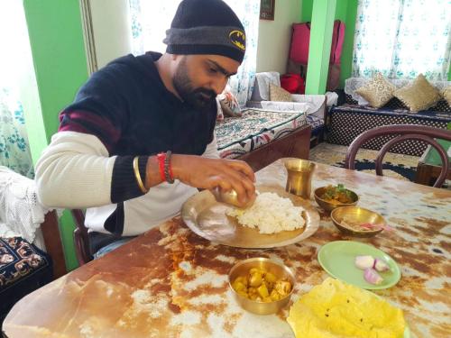a man preparing food on a plate on a table at International Youth Hostel and Homestay Kurseong Bazar in Kurseong