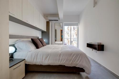 a white bedroom with a bed and a window at Central Sliema 3-Bedroom Retreat in Sliema