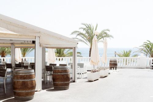 a restaurant with barrels and chairs and the ocean at Estudio I ideal para parejas en la playa Alguer in L'Ametlla de Mar