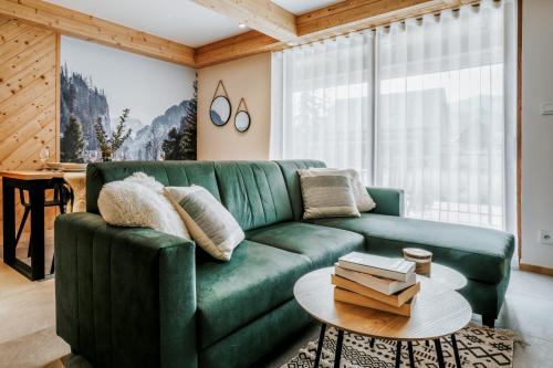 a living room with a green couch and a table at Apartamenty Krokus przy Polanie Biały Potok in Witów