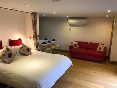 um quarto com uma cama grande e um sofá vermelho em Fantastic Cotswolds hideaway Cleeve Hill em Southam