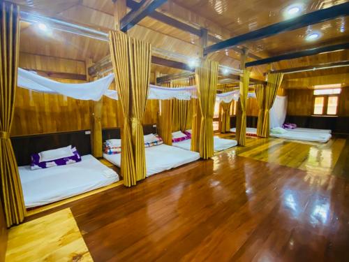 a room with two beds and a wooden floor at Thai Culture Homestay in Mù Cang Chải