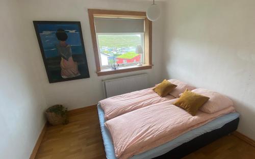 a bed sitting in a room with a window at Cosy house near airport in Sørvágur