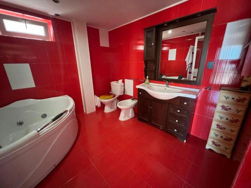 La salle de bains rouge est pourvue d'une baignoire, de toilettes et d'un lavabo. dans l'établissement Villa Niki, à Tulcea