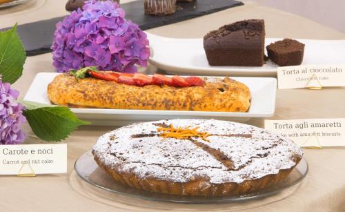 a table with cakes and desserts on plates and purple flowers at Cà Del Moro Resort & SPA in Pontremoli