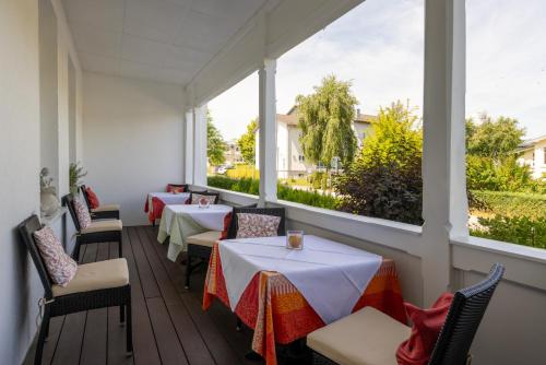 een restaurant met tafels, stoelen en ramen bij Hotel Waldperle in Göhren
