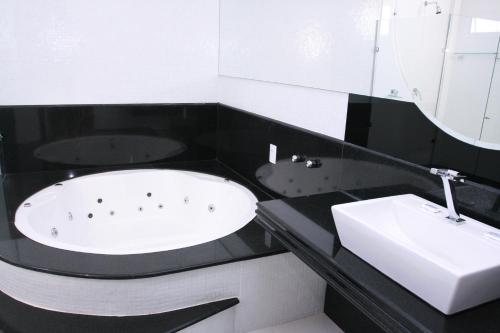 a bathroom with a bath tub and a sink at Hotel Arezzu in Linhares