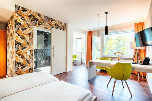 ベルリンにあるホテル カロリーネンホーフのベッド、デスク、シンクが備わるホテルルームです。