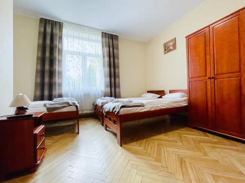 ラプカにあるParkowa Rezydencja Hubalのベッド3台、大きな窓が備わる客室です。