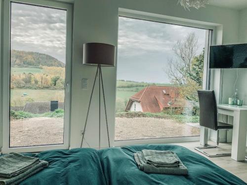 Schlafzimmer mit einem Bett, einem Schreibtisch und einem großen Fenster in der Unterkunft Modernes Doppelzimmer Friedewald Rhönblick in Friedewald