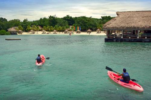 two people in kayaks in the water near a beach at Bluewater Maribago Beach Resort in Mactan