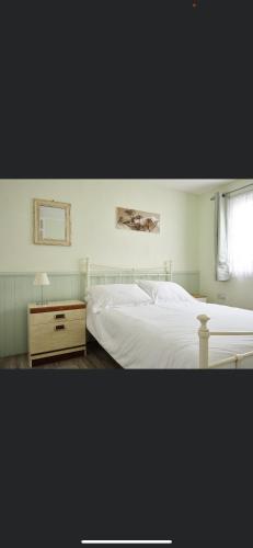 a bedroom with a white bed and a window at Butterfly Chalets Norfolk in Scratby