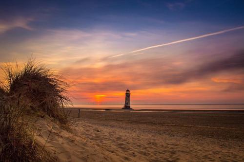 a lighthouse on the beach with a sunset at 2 Bedroom Static Caravan C3 on quiet park near Talacre and Prestatyn in Prestatyn