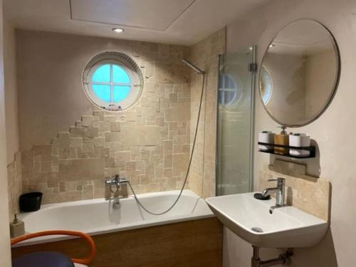 a bathroom with a sink and a tub and a mirror at Artistic spacious flat in central Brixton in London