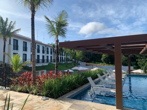 a resort with a swimming pool with chairs and palm trees at Quinta Santa Bárbara Pirenópolis in Pirenópolis