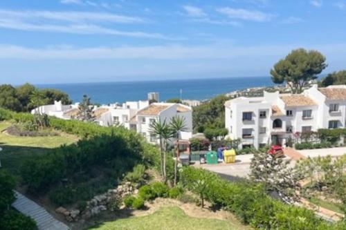 a house on a hill with the ocean in the background at Rancho Miraflores Seaview Studio in La Cala de Mijas