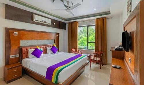 アレッピーにあるTreebo Premium Palmyra Milford, 2 Km From Alleppey Beachのベッドとテレビのある寝室
