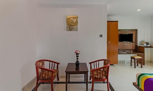 アレッピーにあるTreebo Premium Palmyra Milford, 2 Km From Alleppey Beachのテーブルと椅子2脚のあるリビングルーム