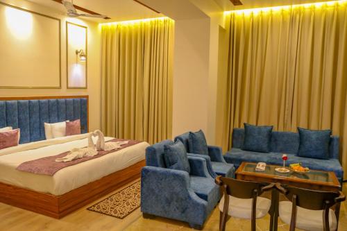 a bedroom with a bed and a chair and a table at Four Leaf Hotel, Kasganj in Kāsganj