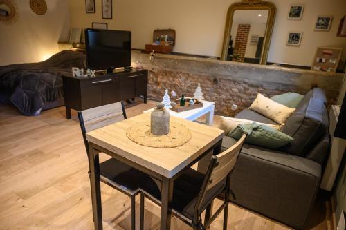 ein Wohnzimmer mit einem Tisch und einem Sofa in der Unterkunft gîte Cosy Green 2 in Chevincourt