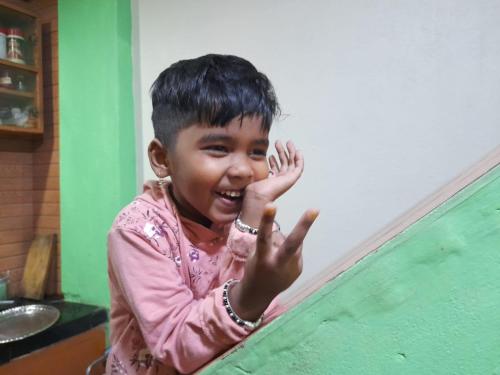 a young child smiling and waving at the camera at International Youth Hostel and Homestay Kurseong Bazar in Kurseong