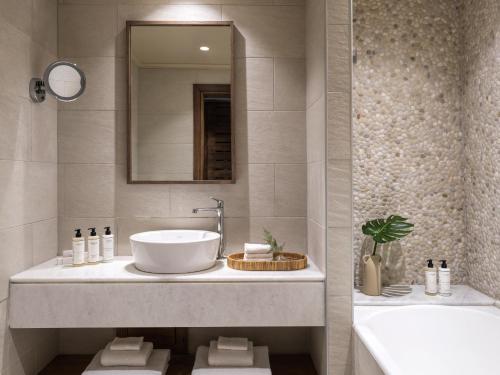 a bathroom with a sink and a mirror and a tub at Lindian Village All Inclusive Resort Rhodes,Curio Collection in Kiotari