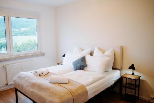 a bedroom with a large white bed with a window at Jenapartments Zuhause auf Zeit, Uniklinik & Natur vor der Tür in Jena