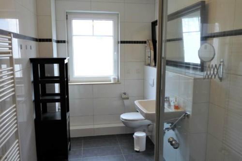 een badkamer met een toilet, een wastafel en een raam bij MeinStrandNest in Juliusruh